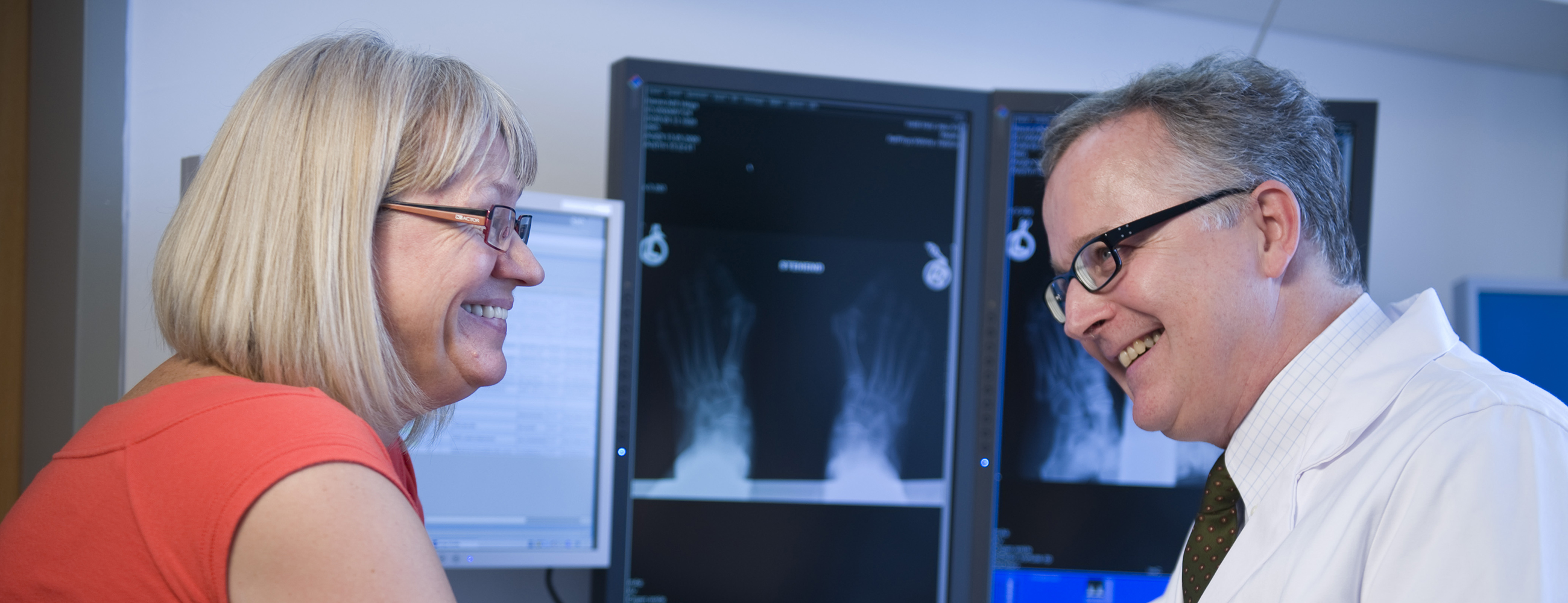 Blonde Patientin im Gespräch mit Arzt vor einem Röntgenbild